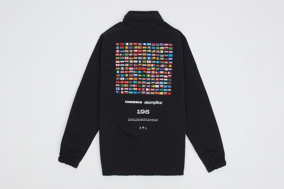 Back image of black nylon 1/4 zip pullover with screen printed image of 195 flags from countries of the world text underneath graphic reads ' Umbro , Akomplice 195 there are over 7 billion people living in 195 countries on this planet. World peace is an individual and collective responsibility'.
