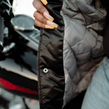 Close-up of a woman exposing the padded inside of a striped heavyweight satin jacket. 