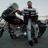 A woman sitting on a motorbike in a striped satin jacket with a California Oaklandish wordmark and Oaklandish tree logo.