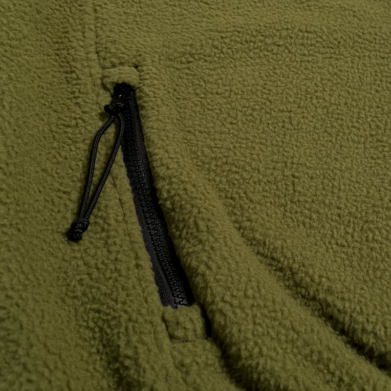Detailed close up of front pocket zipper with black pull cord on green polar Oaklandish fleece.