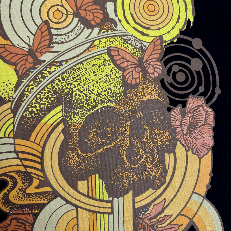 Detailed close-up of swirl design symbolizing rebirth featuring butterflies with a skull at the center on a black cotton t-shirt.