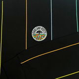 Close-up of Oakland Roots SC crest on wearer's left chest on black crewneck sweatshirt with multicolor pinstripes.