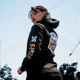 Woman outdoors in black  hoodie showing Roots SC wordmark on sleeve and circle logo on back.