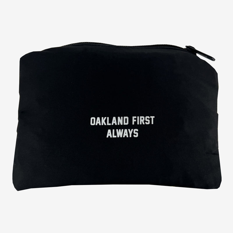 Black  slde of a packing pouch for a black Roots SC zip-up hoodie with white “ALWAYS FIRST OAKLAND” wordmark. 