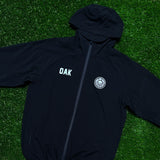 Black zip-up hoodie with white OAK wordmark on right chest, and Roots SC round logo on left chest laying on grass.