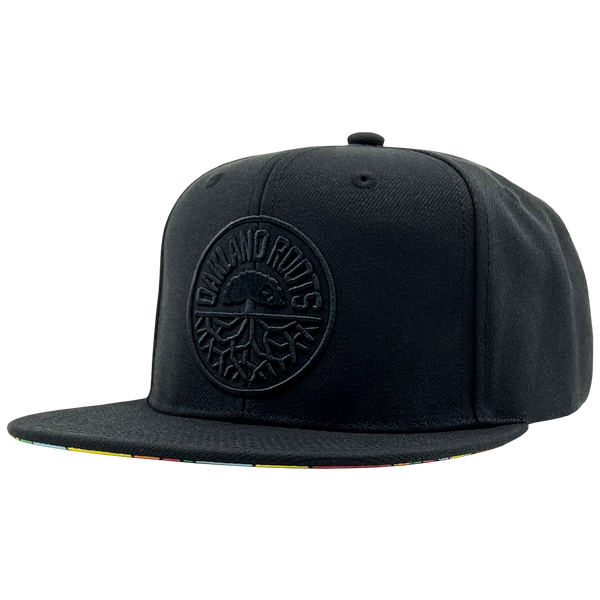 Side view of black Mitchell & Ness snapback truckers cap with black Roots SC logo.