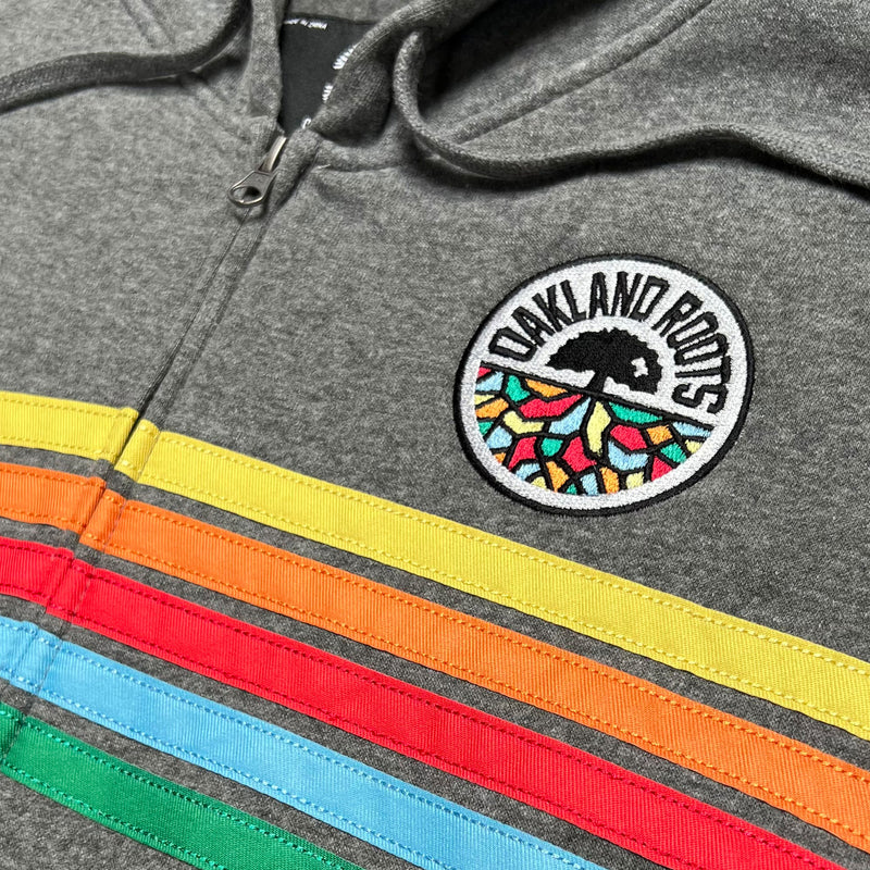 Detailed close up of gunmetal Heather full zip hoodie with green, blue, red, orange and yellow stripes and full-circle Roots SC mosaic logo on the chest.