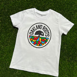 White youth t-shirt with full-color Roots SC circle logo on the chest laying on the grass.