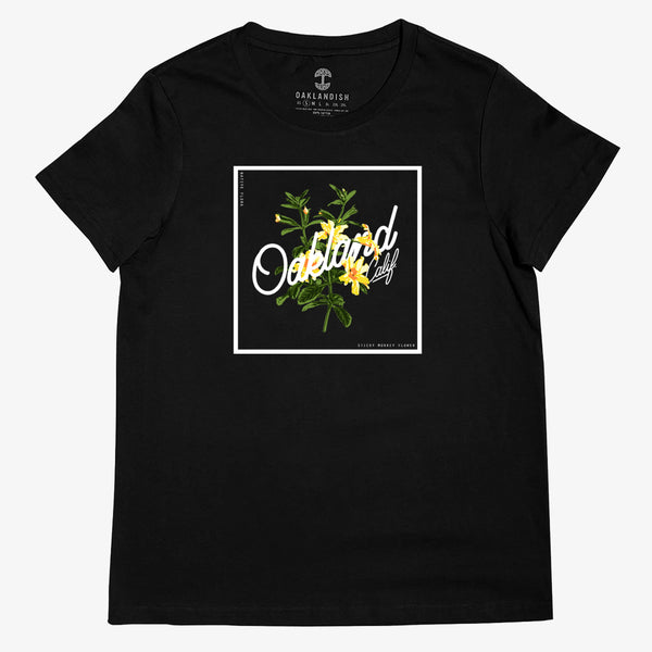 Women’s cut t-shirt with a graphic of yellow sticky monkey flowers overlaid with cursive Oakland wordmark in a white square.