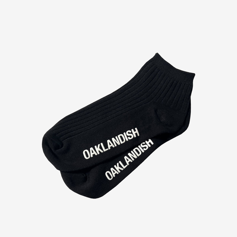 Men's Crew Socks in black without packaging. Oaklandish text in white across sole.