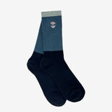 Two nestled high-cut color blocked black, blue, and grey crew socks with an embroidered pink Oaklandish logo at the top.