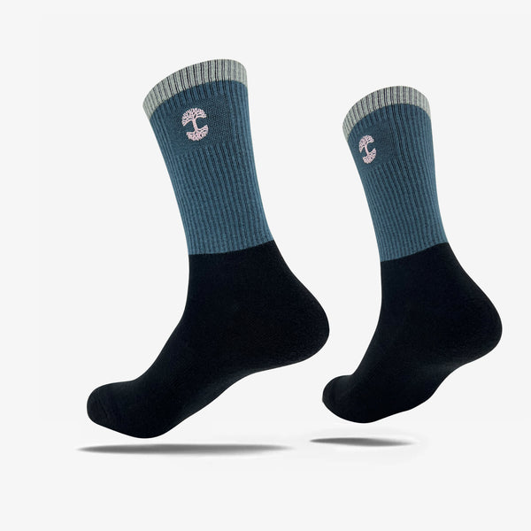 High-cut color blocked black, blue, and grey crew socks with an embroidered pink Oaklandish logo at the top.