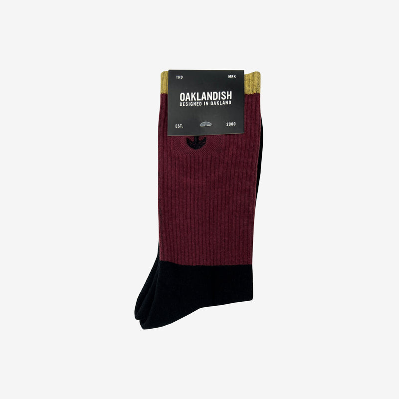 High-cut color blocked crew socks (black, maroon & brown)  folded into an Oaklandish retail package.