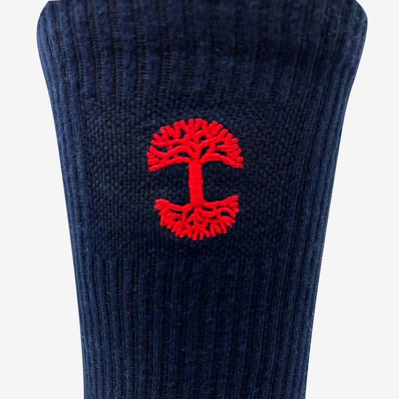 Close up of red embroidered Oaklandish logo at the top of navy men’s crew socks.