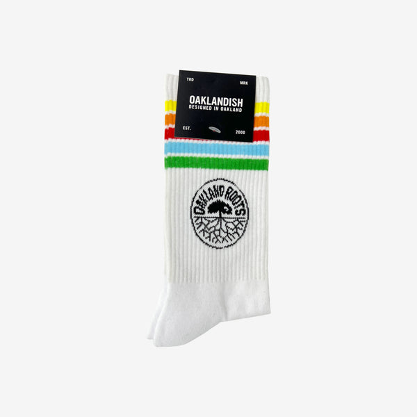 White crew socks with Oakland Roots Soccer Club colored stripes & logo on top sides in Oaklandish retail packaging.