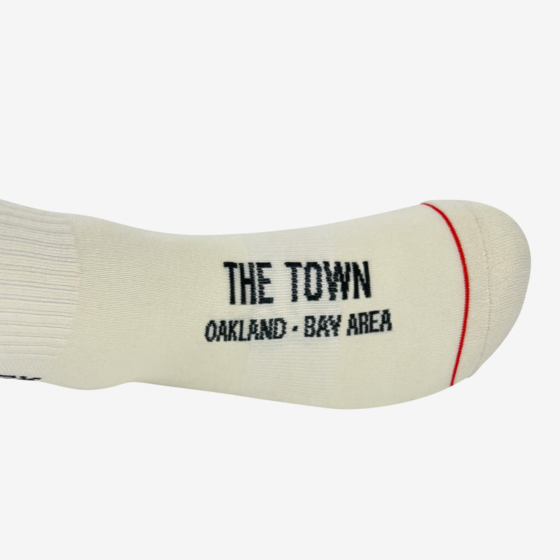 Close up of top view of words The Town, Oakland Bay Area in capital letters on the top foot region of a white crew sock.