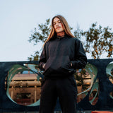 Man outside wearing a black Oaklandish hoodie and jogger set.