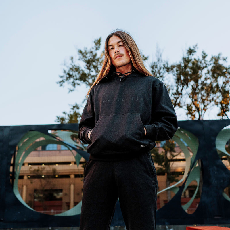 Man outside wearing a black Oaklandish hoodie and jogger set.