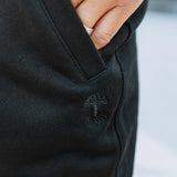 Detailed close-up of a hand in the zipped pocket of black joggers.