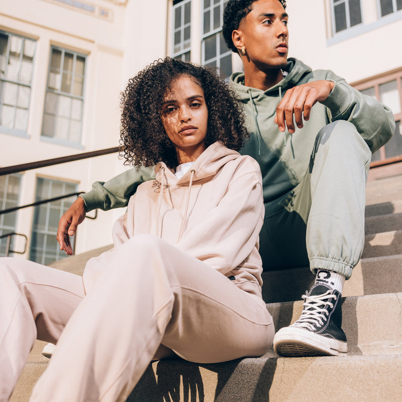 Female and Male model sitting outside on steps in Army and Sand Oaklandish standard sweatsuit sets.