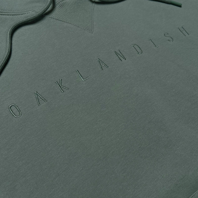 Detailed close-up of army standard pullover sweatshirt with monochromatic Oaklandish embroidered on chest.