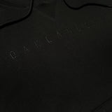 Detailed close-up of black pullover hoodie with monochromatic Oaklandish wordmark embroidered on chest.