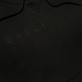 Detailed close-up of black pullover sweatshirt with monochromatic Oaklandish wordmark embroidered on chest.