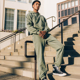 A man standing outside on steps wearing a matching army green Oaklandish hoodie and jogger set.