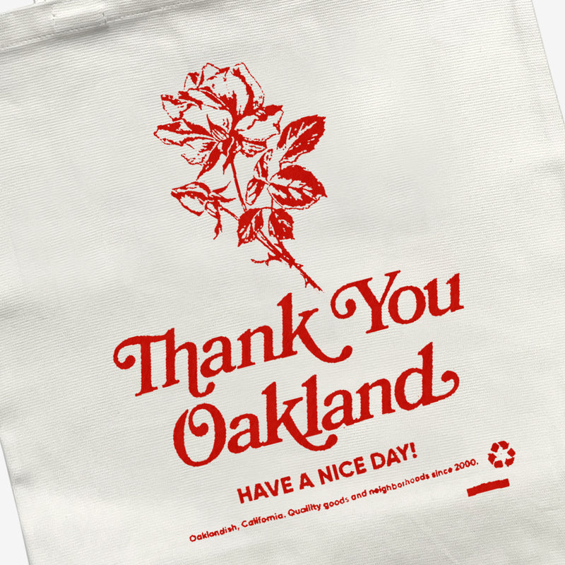Close up of hand-drawn red flower and the words “Thank-You Oakland. Have a Nice Day” on a cream reusable shopping tote bag.