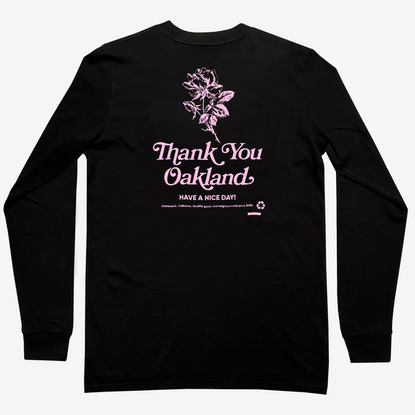 Long-sleeve black t-shirt with pink graphic of a flower with the words “Thank-You Oakland. Have a Nice Day”.