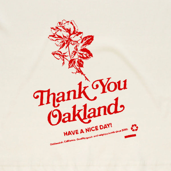 Close-up of a hand-drawn red flower and the words “Thank-You Oakland. Have a Nice Day” on a white t-shirt.