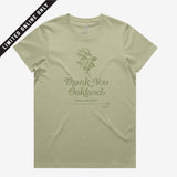 Khaki women’s tee with green graphic with a flower and the words “Thank-You Oakland. Have a Nice Day”.