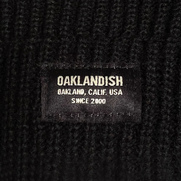 Close-up of Oaklandish square patch on the front cuff of a black beanie.