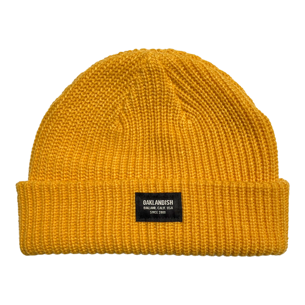 Gold short knit beanie with Oaklandish square patch on the front cuff.