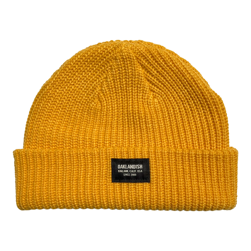 Gold short knit beanie with Oaklandish square patch on the front cuff.