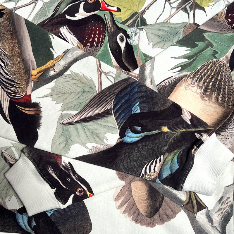 Close up of sleeves on cream wood duck all over print crewneck sweatshirt.