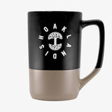 The backside of a black and tan two-tone stoneware mug with the Oaklandish wordmark circling the Oaklandish tree logo.