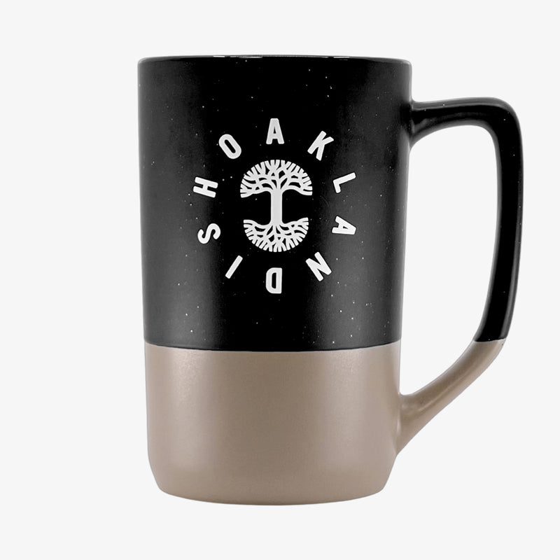 The backside of a black and tan two-tone stoneware mug with the Oaklandish wordmark circling the Oaklandish tree logo.