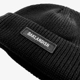 Close up of black shorter style cuff beanie with white Oaklandish wordmark on cuff patch.