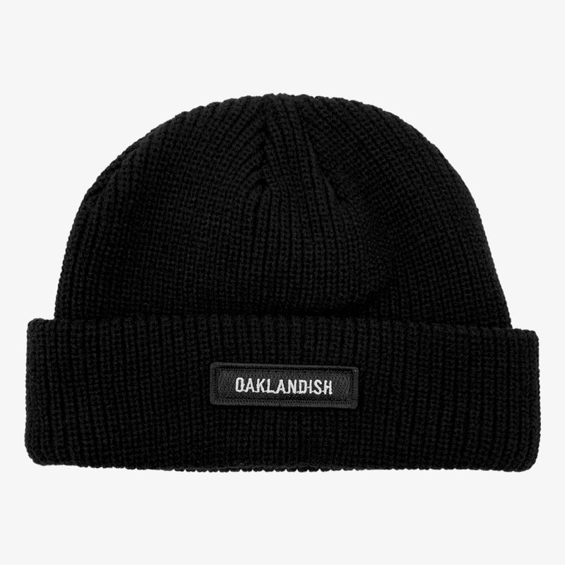 Black shorter style cuff beanie with white Oaklandish wordmark on cuff patch.