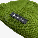 Close-up of shorter style olive green cuff beanie with white Oaklandish wordmark on a black patch on cuff.