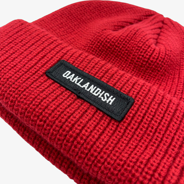 Close-up of shorter style burgundy cuff beanie with white Oaklandish wordmark on cuff patch.