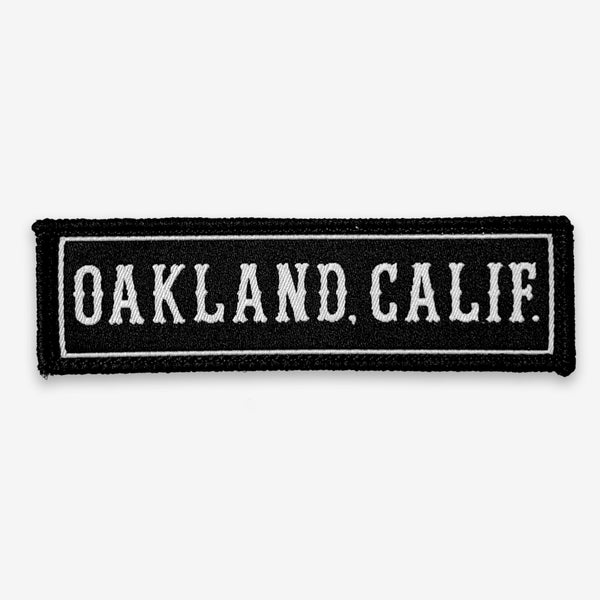 Black rectangle fabric iron patch, outlined with white line and capitalized word mark “OAKLAND. CALIF.”