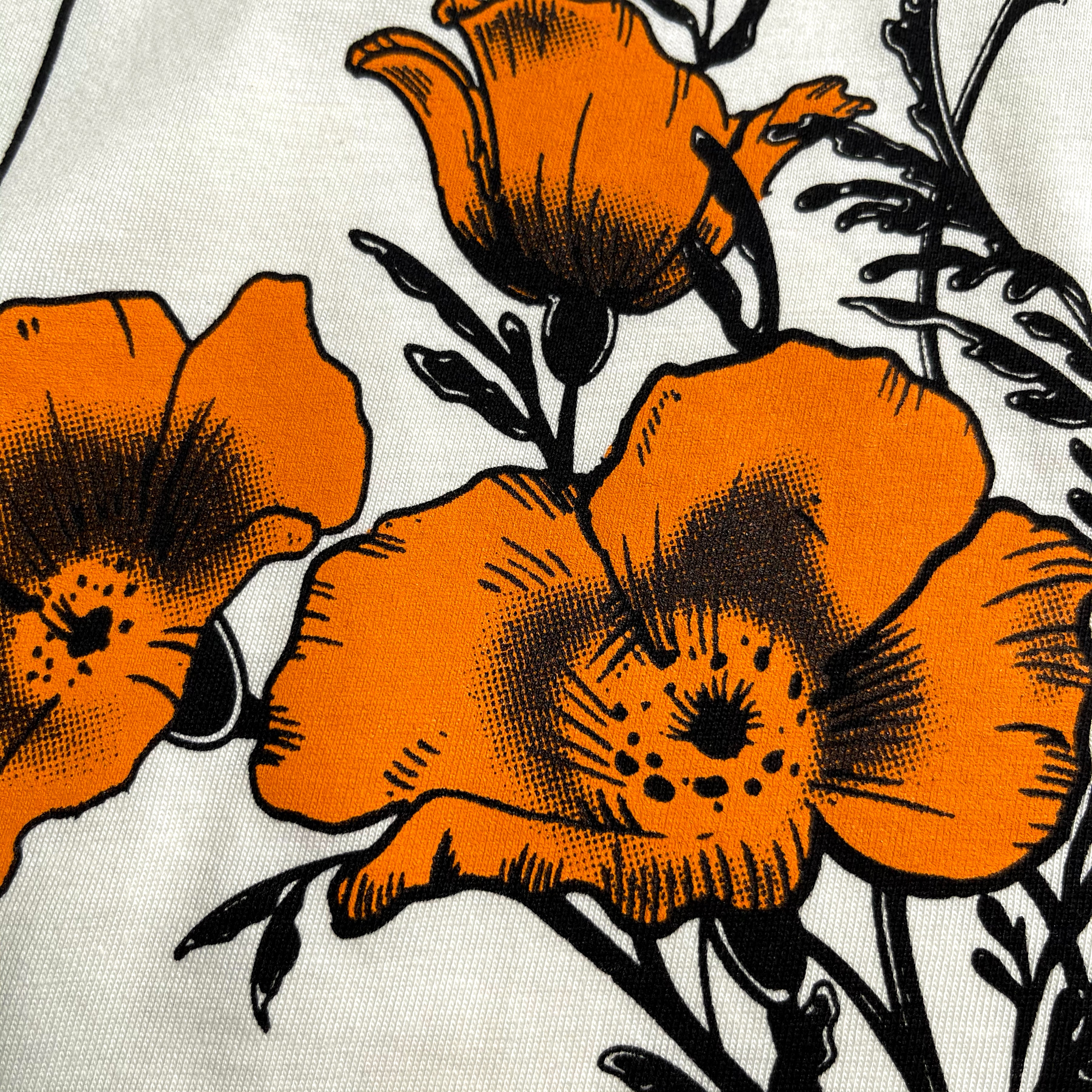 Close-up of California poppies on the chest of a women’s natural-color cotton t-shirt.