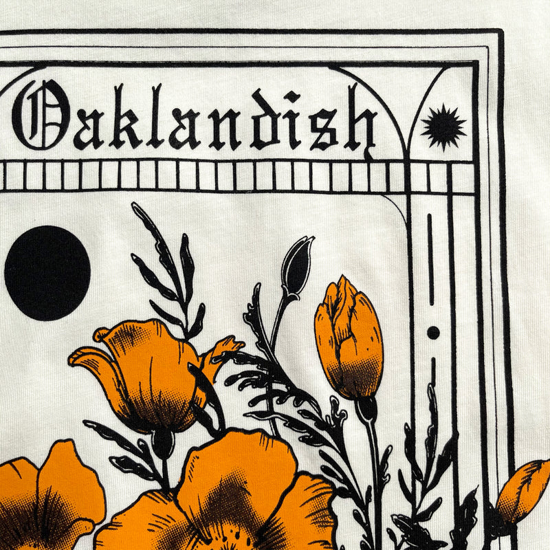 Close-up of Oaklandish wordmark and poppies graphic on a natural-color cotton t-shirt.