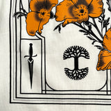 Close-up of Oaklandish tree logo, sword, and a poppy on a natural-color cotton t-shirt.