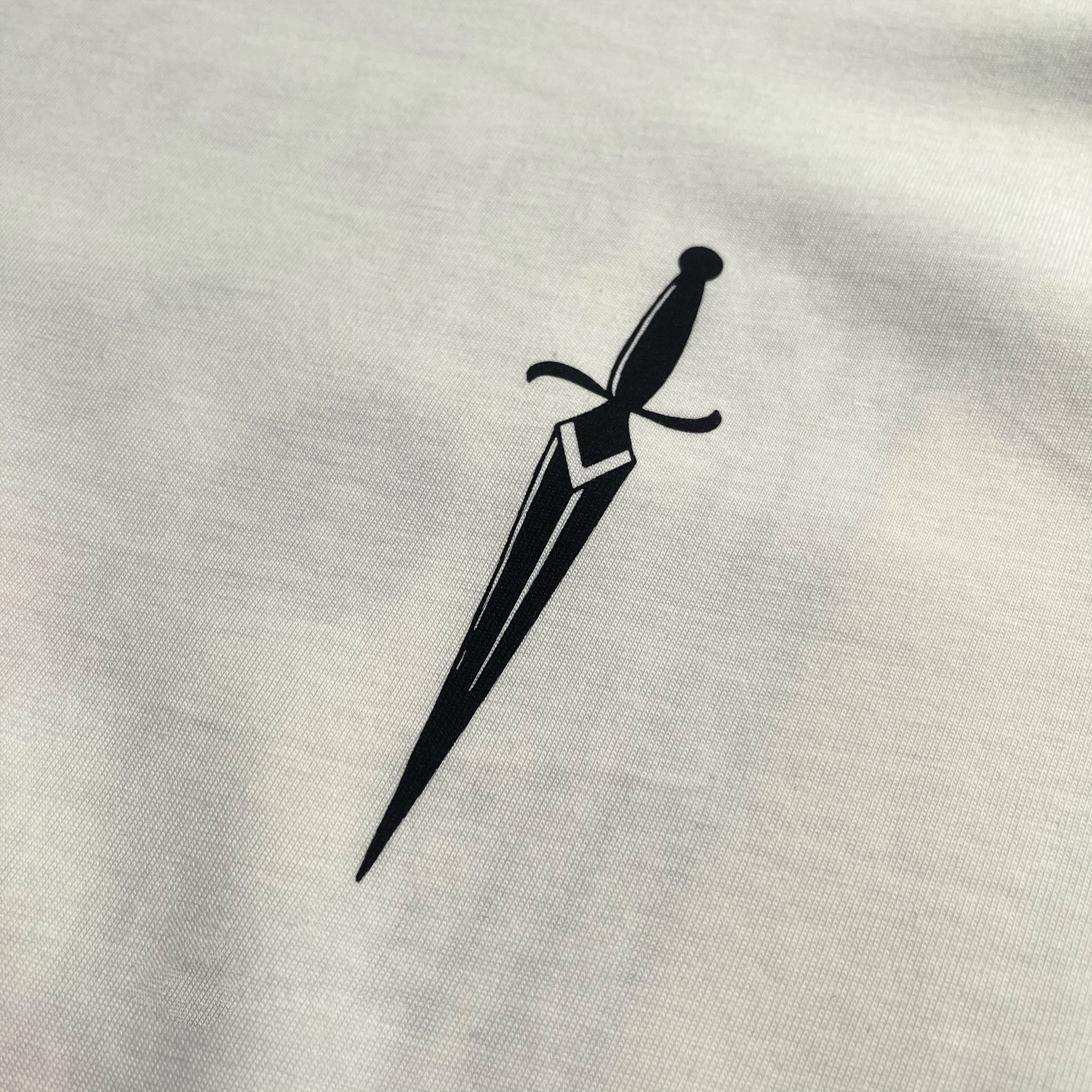 Close-up of sword graphic on the front chest of a natural-color cotton t-shirt.