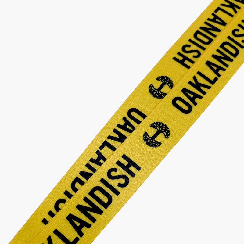 Close up of black Oaklandish word mark and tree logo on a yellow lanyard.