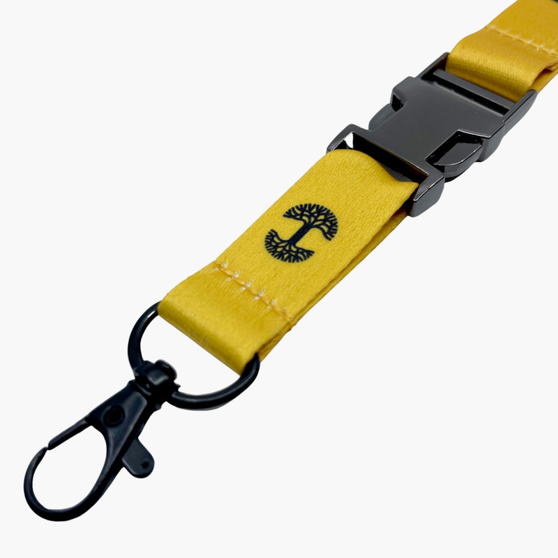 Close up detachable clip with black Oaklandish tree logo on a yellow lanyard.
