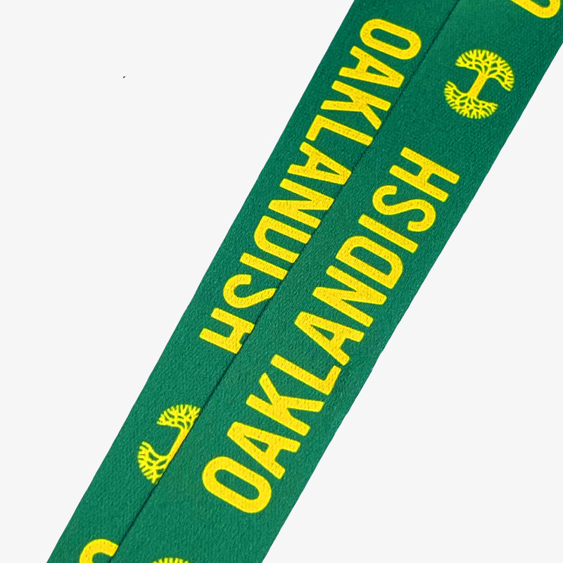 Close up of yellow Oaklandish word mark and tree logo on a green lanyard.